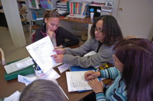 A teacher and three students go over a worksheet together.